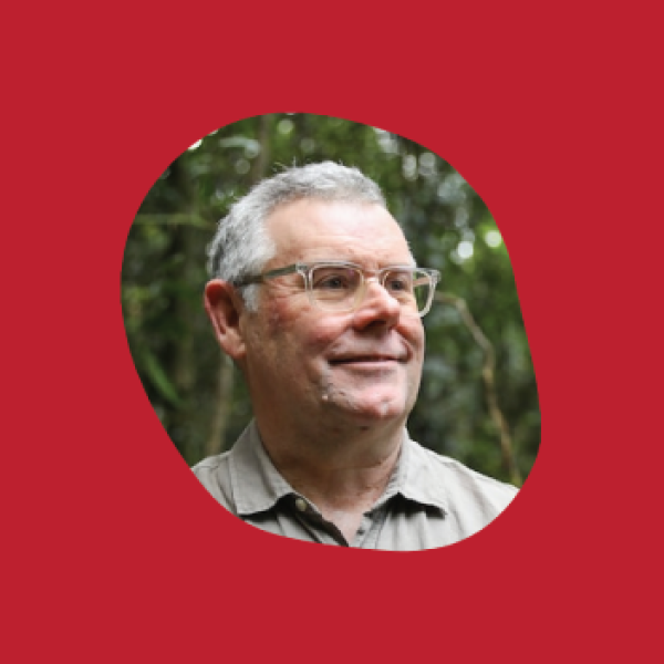 A photo of a man with glasses in a brown shirt in an organic pebble shape. It sits on a red background.