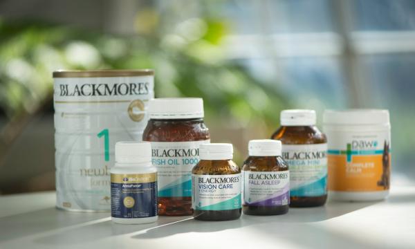 Seven Blackmores bottles of vitamins and baby formula sit on a white table.